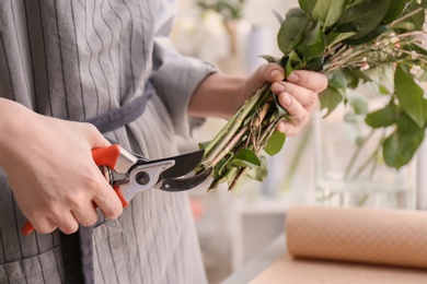 Photo of Female florist pruning stems at workplace, closeup