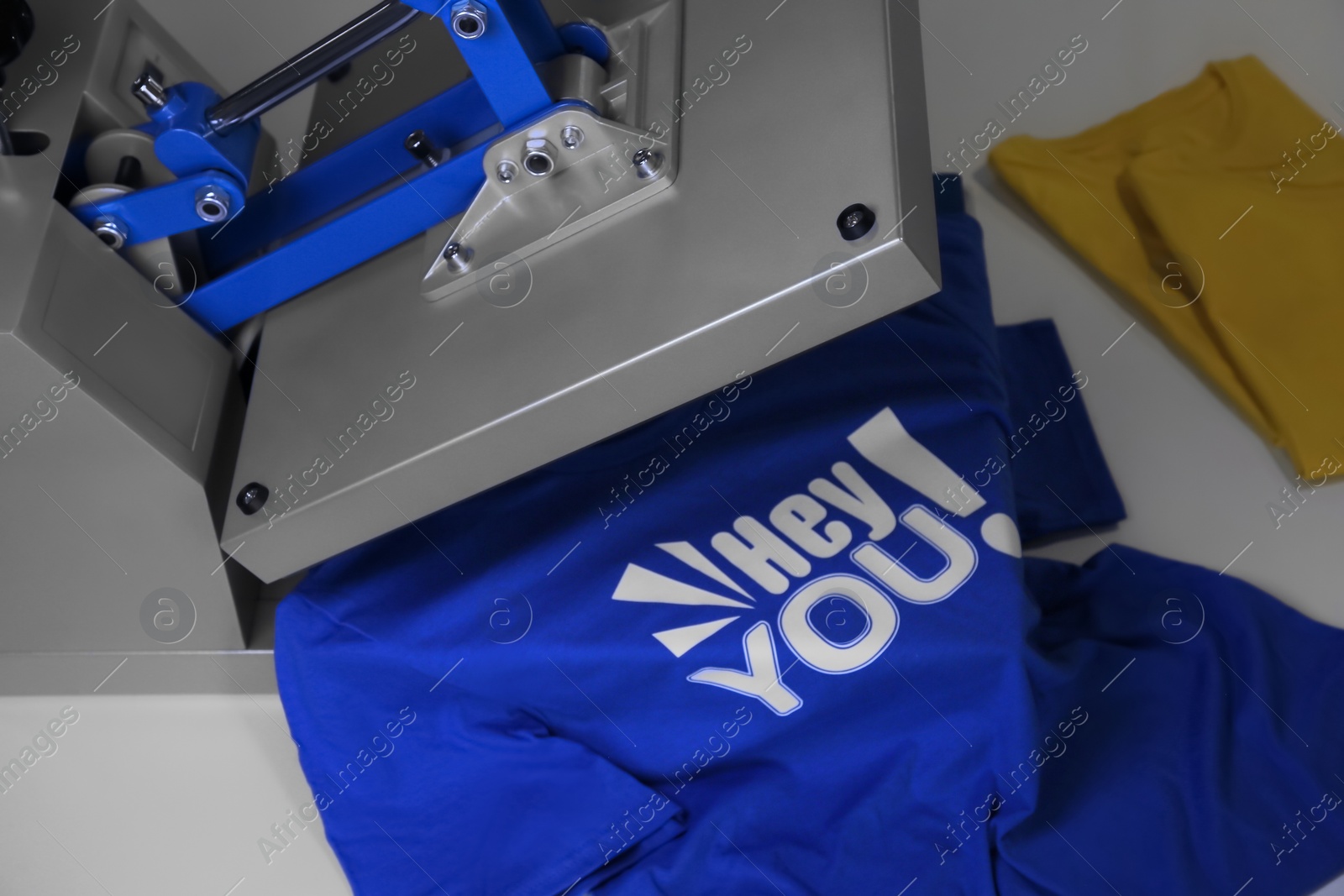 Photo of Printing logo. Heat press with t-shirt on white table