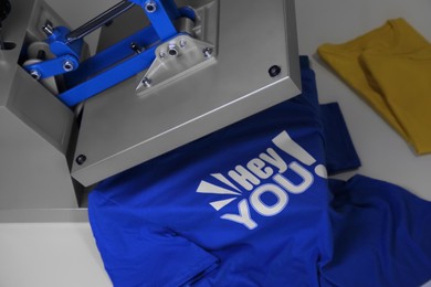 Photo of Printing logo. Heat press with t-shirt on white table