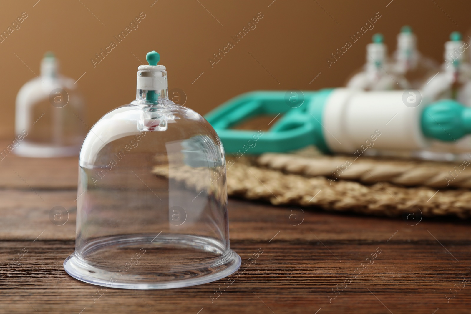Photo of Cupping therapy. Plastic cup on wooden table, closeup. Space for text
