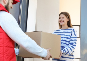 Woman receiving parcel from delivery service courier indoors