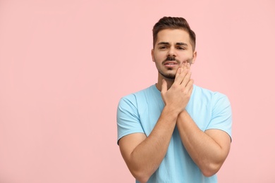 Young man suffering from strong tooth pain on color background, space for text