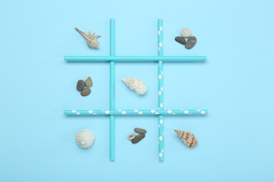 Tic tac toe game made with sea treasures on light blue background, top view