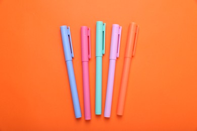 Photo of Many colorful markers on orange background, flat lay