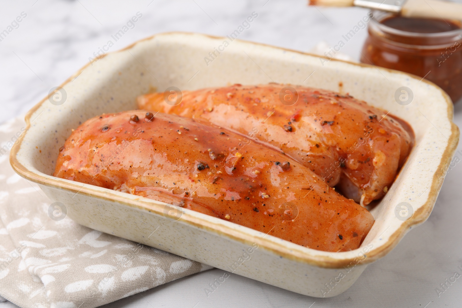 Photo of Raw marinated chicken fillets on white marble table, closeup