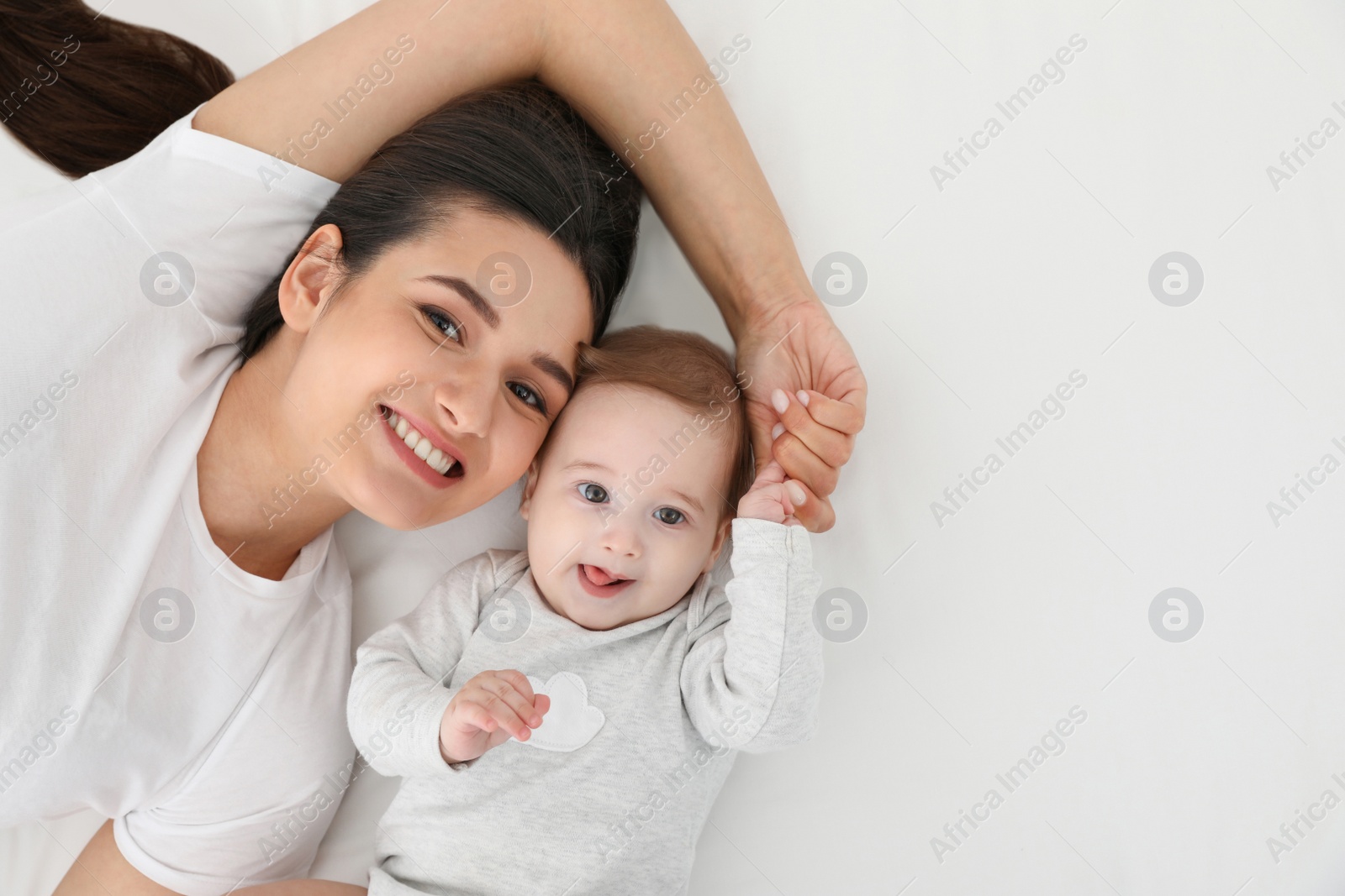 Photo of Portrait of mother with her cute baby lying on bed, top view. Space for text