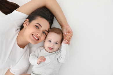 Portrait of mother with her cute baby lying on bed, top view. Space for text