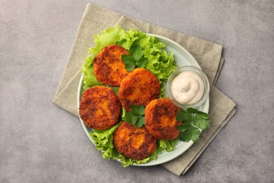 Tasty vegan cutlets with sauce on light grey table, top view