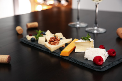 Photo of Different types of delicious cheeses with berries and nuts on table