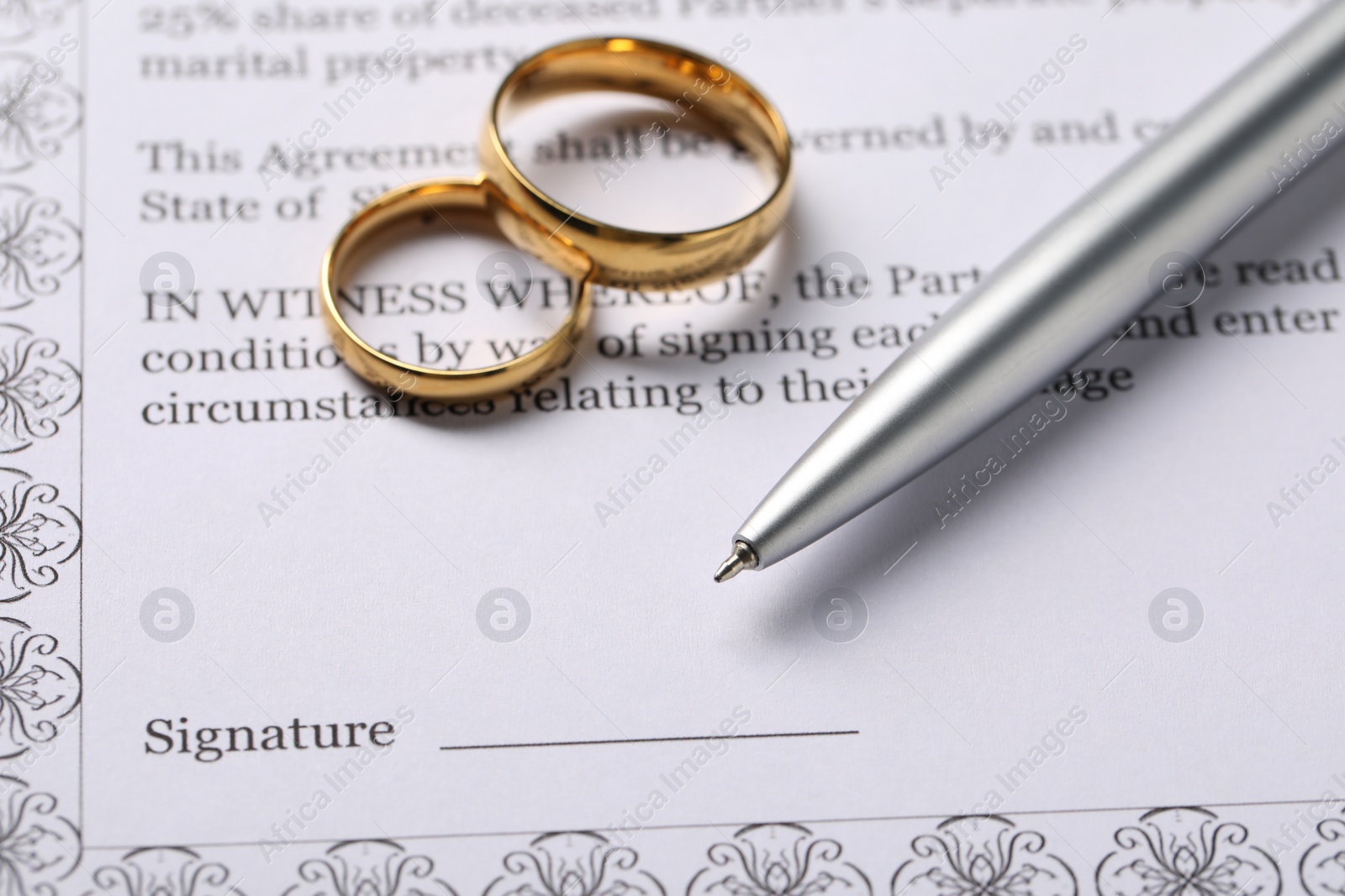 Photo of Marriage contract, gold rings and pen on table, closeup