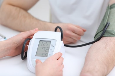 Photo of Doctor checking blood pressure of man in clinic, closeup