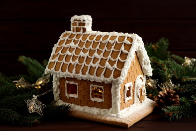 Beautiful gingerbread house decorated with icing and fir branch on wooden table