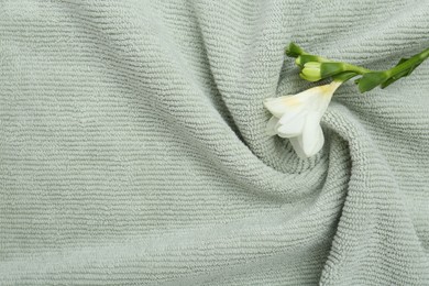 Photo of Freesia flower on soft towel, top view. Space for text