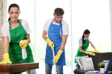 Team of professional janitors in uniform cleaning office