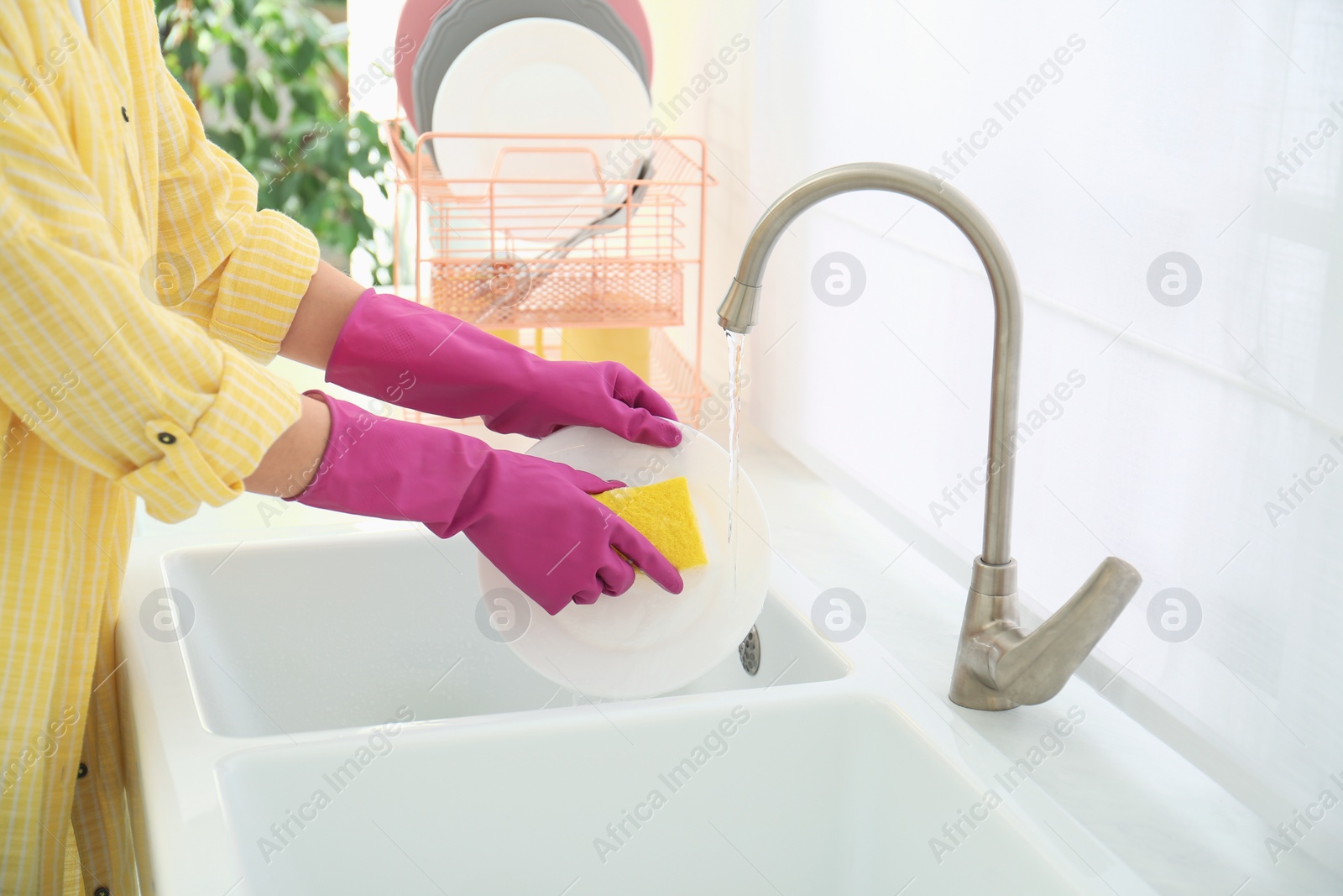 Photo of Woman washing ceramic plate in kitchen, closeup