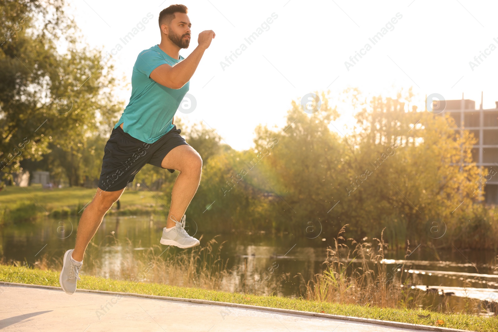 Photo of Young man running near pond in park. Space for text