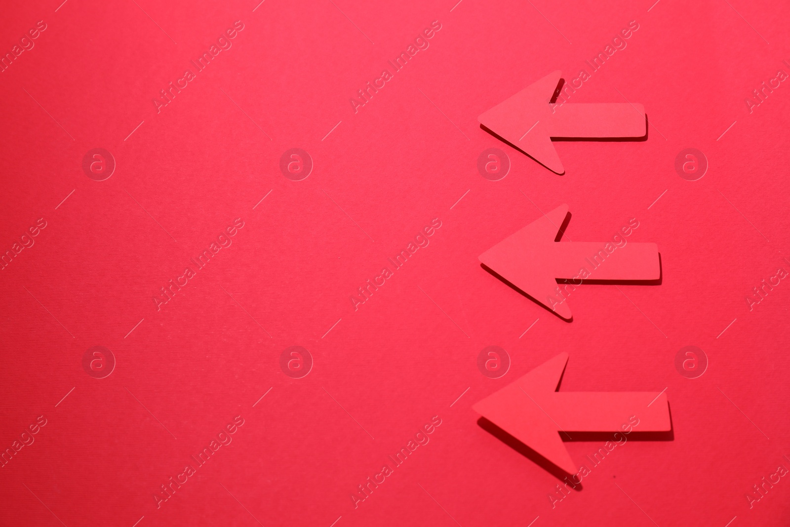 Photo of Paper arrows on red background, flat lay. Space for text
