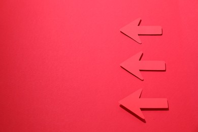 Paper arrows on red background, flat lay. Space for text