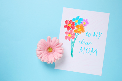 Photo of Handmade greeting card for Mother's day and flower on light blue background, flat lay