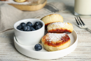 Photo of Delicious cottage cheese pancakes with blueberries and sugar powder on white wooden table
