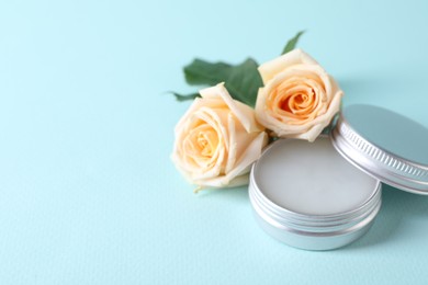Lip balm and rose flowers on light blue background, space for text