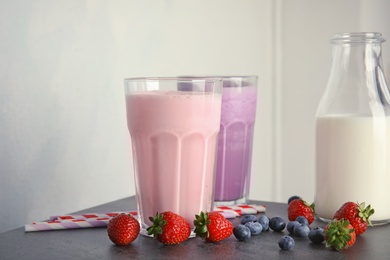 Delicious milk shakes and ingredients on table against light background