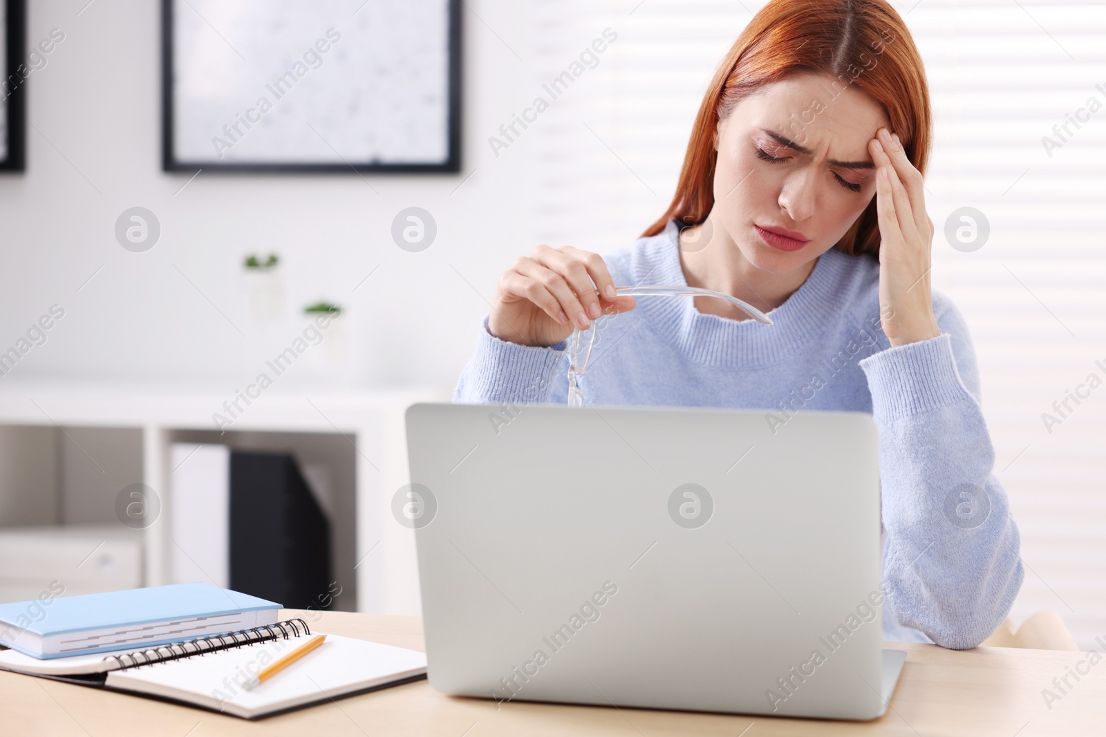 Photo of Woman with glasses suffering from headache at workplace in office, space for text