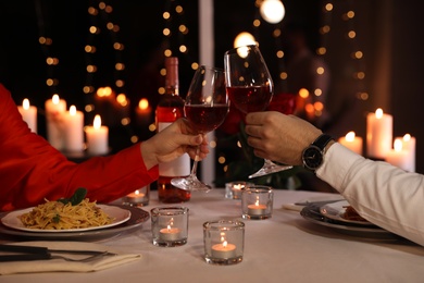 Photo of Couple clinking glasses of wine in restaurant, closeup. Romantic dinner