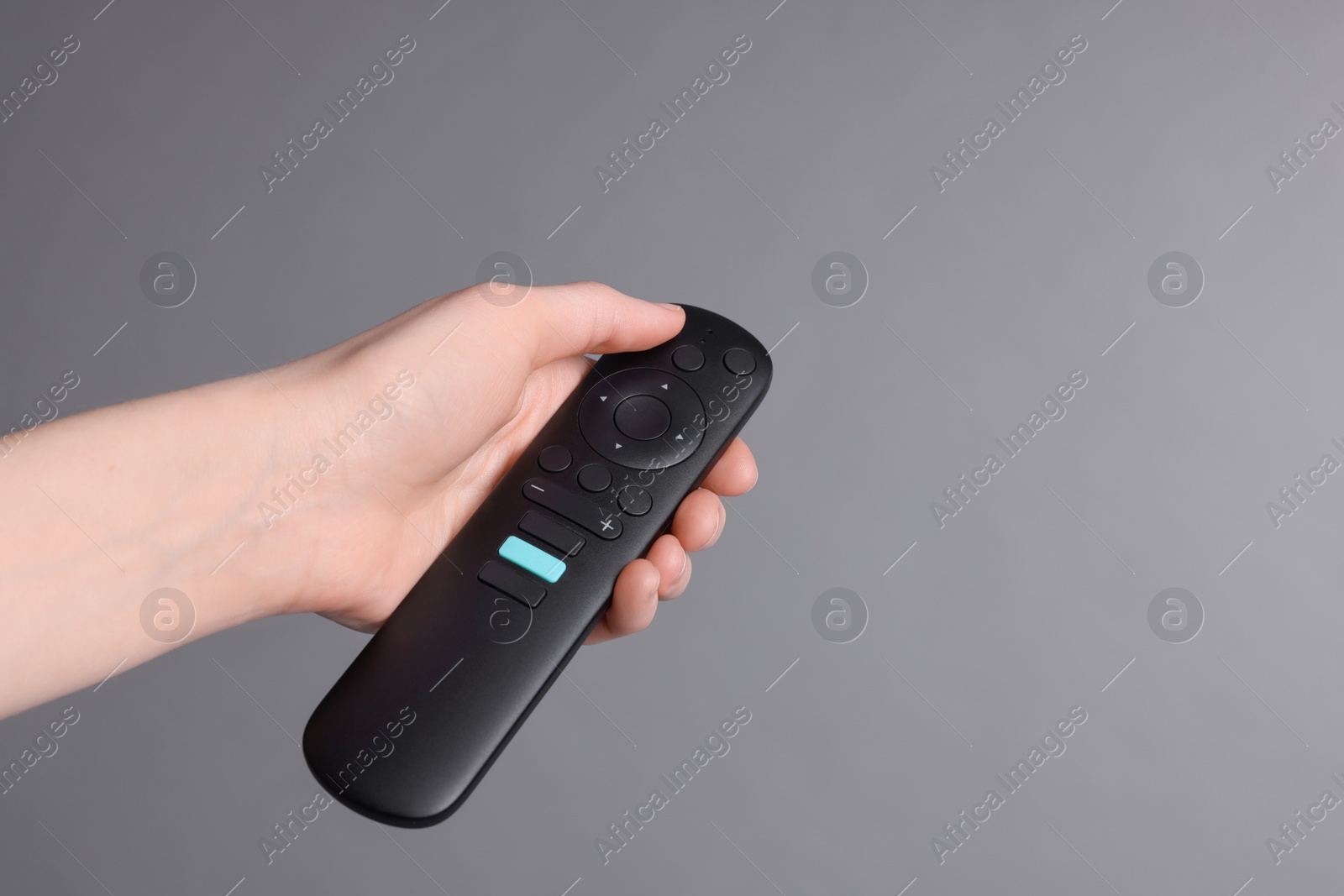 Photo of Woman holding TV remote control on grey background, closeup. Space for text