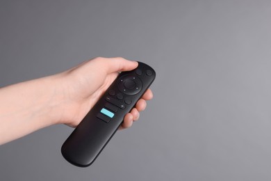 Photo of Woman holding TV remote control on grey background, closeup. Space for text