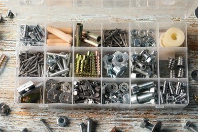 Photo of Organizer with many different fasteners on rustic wooden table, flat lay