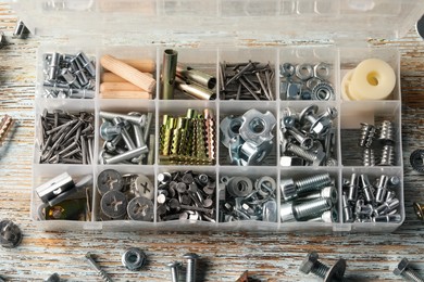 Organizer with many different fasteners on rustic wooden table, flat lay