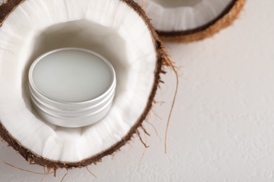 Photo of Lip balm inside coconut on light background, closeup. Space for text