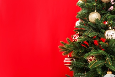 Beautifully decorated Christmas tree against color background, closeup