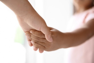 Photo of Children holding hands on light background, closeup. Unity concept