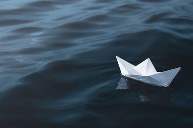 Photo of White paper boat floating on river, space for text