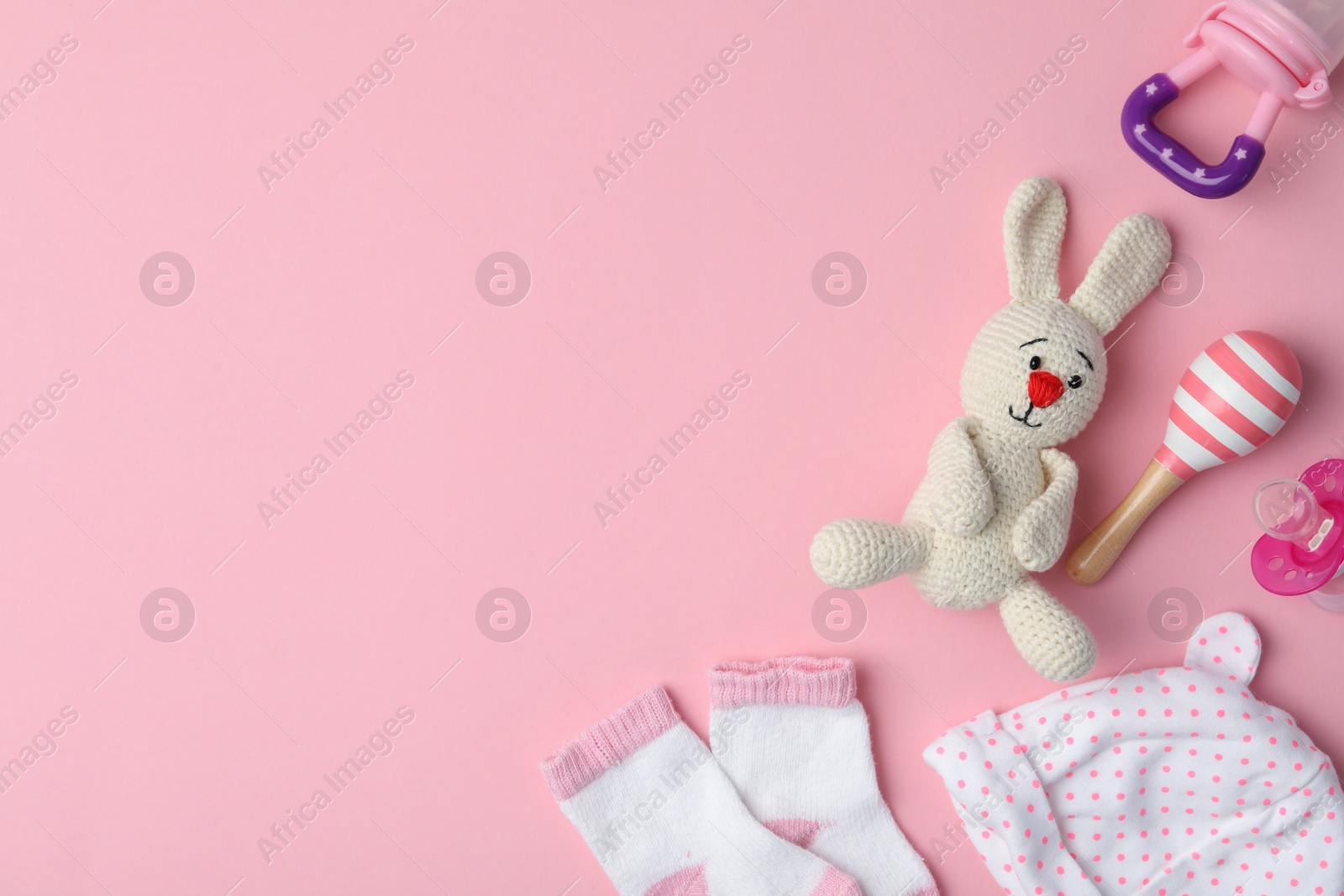 Photo of Flat lay composition with toy bunny and child's clothes on pink background, space for text