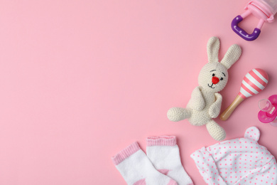 Flat lay composition with toy bunny and child's clothes on pink background, space for text