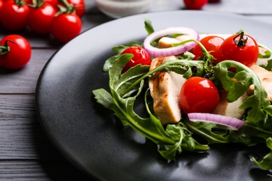 Photo of Delicious salad with chicken, vegetables and arugula on grey table, closeup