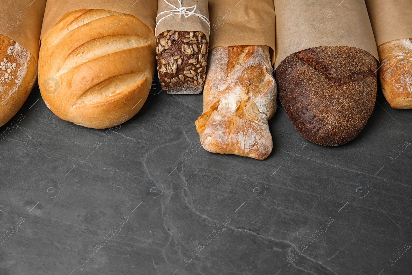 Photo of Different kinds of fresh bread on grey table, space for text