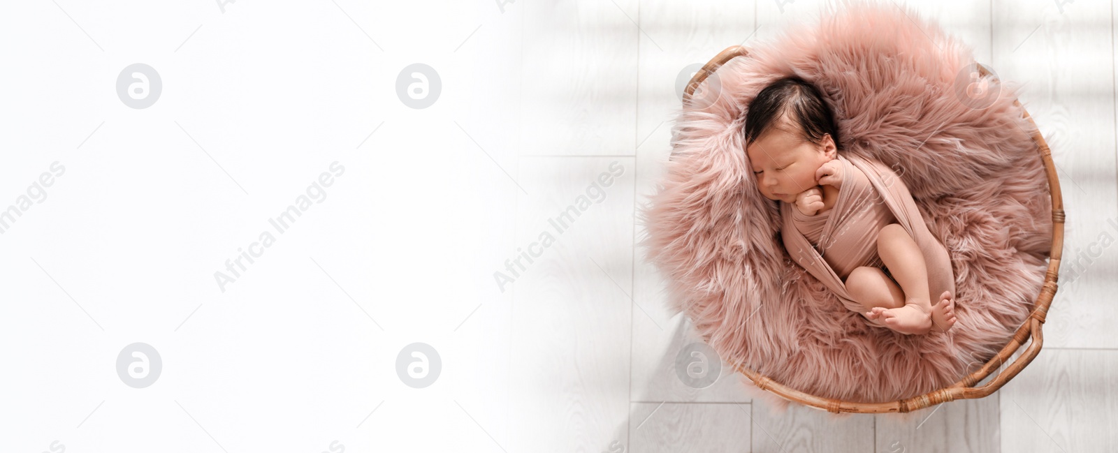 Image of Cute newborn baby sleeping in wicker basket, top view with space for text. Banner design