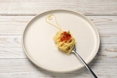 Photo of Heart made with spaghetti and fork on white wooden table