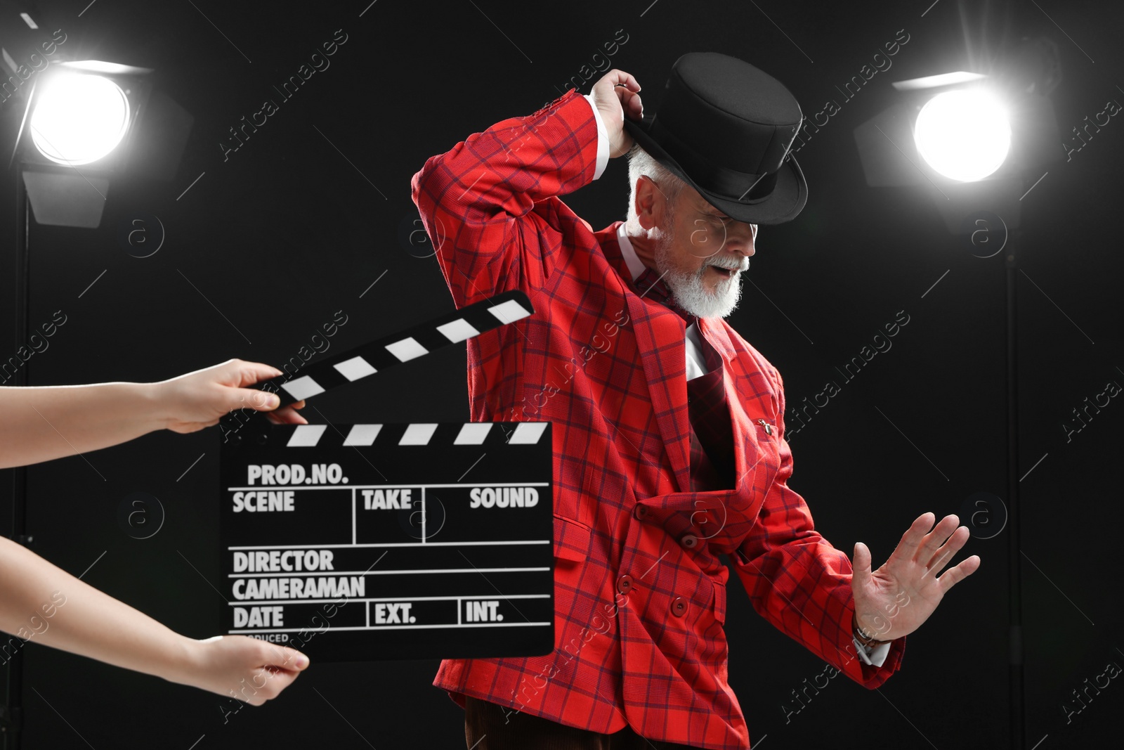 Photo of Senior actor performing role while second assistant camera holding clapperboard on stage. Film industry