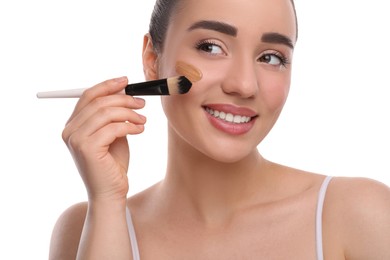 Photo of Woman applying foundation on face with brush against white background