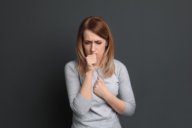 Photo of Young woman coughing on grey background