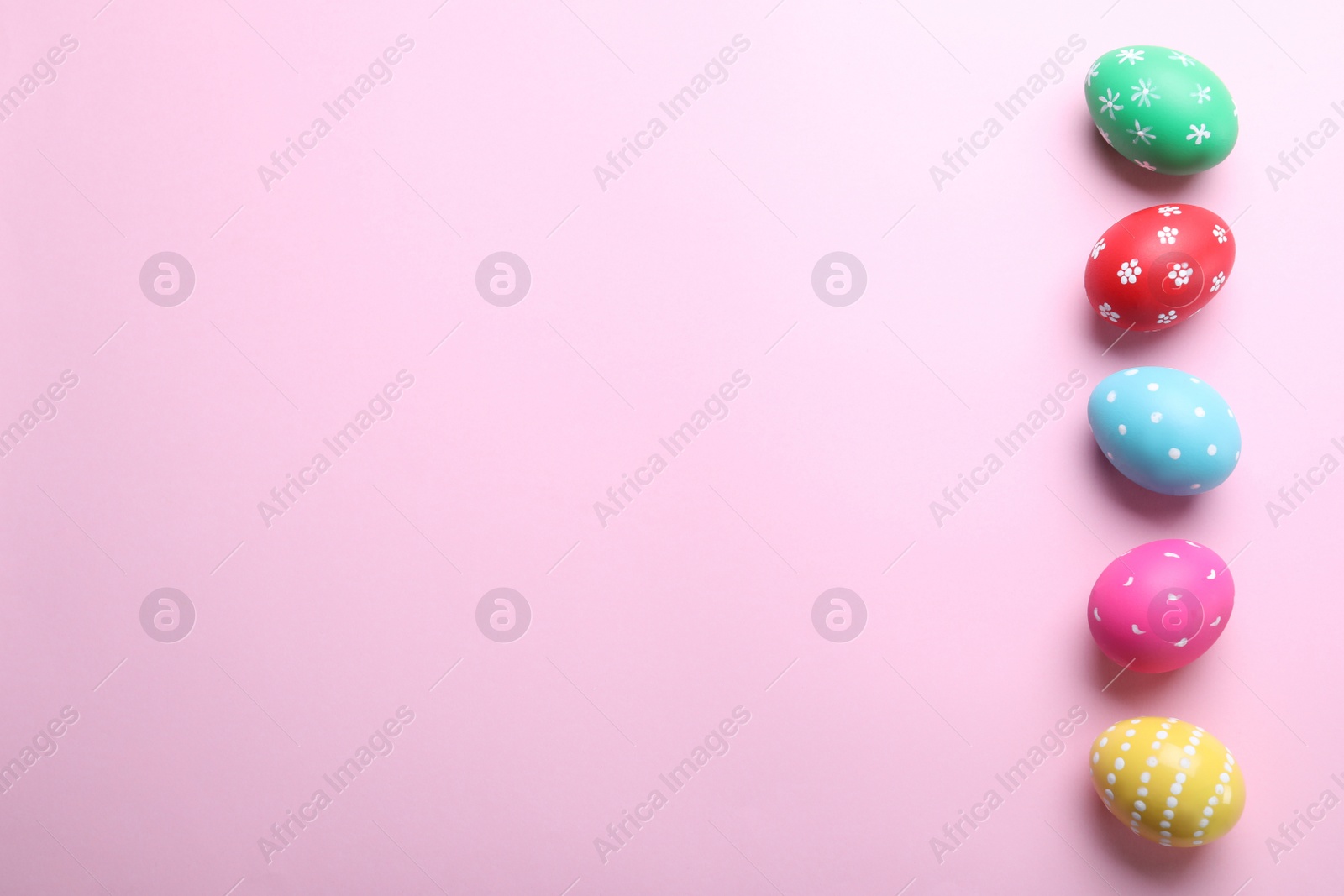 Photo of Bright painted eggs on pink background, flat lay with space for text. Happy Easter