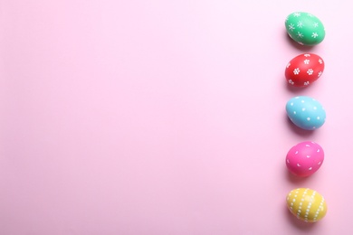 Photo of Bright painted eggs on pink background, flat lay with space for text. Happy Easter