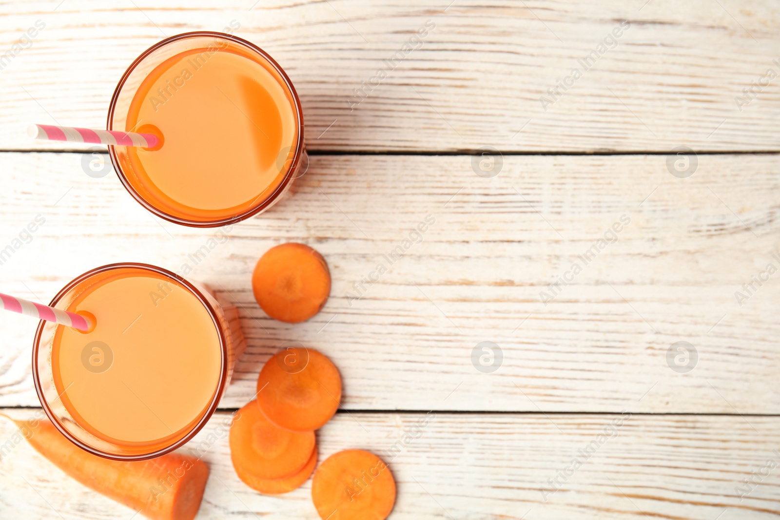 Photo of Freshly made carrot juice  on wooden table, flat lay. Space for text