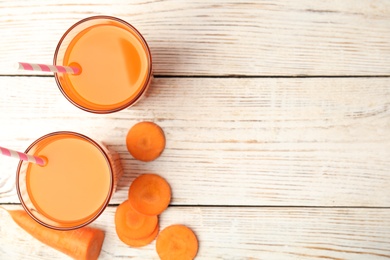 Photo of Freshly made carrot juice  on wooden table, flat lay. Space for text