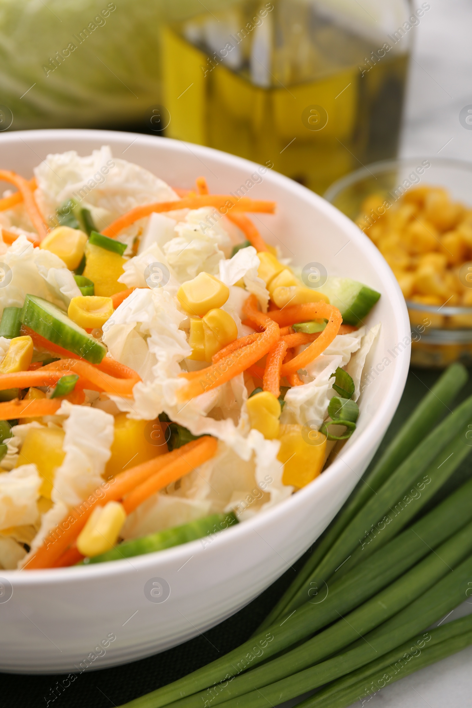 Photo of Tasty salad with Chinese cabbage, carrot, corn, cucumber and green onion on table, closeup